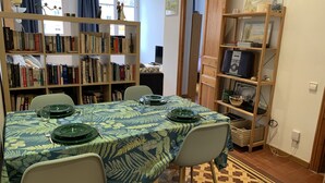 Ein Essbereich mit einem Tisch, gedeckt für vier Personen, umgeben von Bücherregalen voller Bücher.