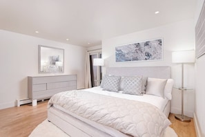 Ein modernes Schlafzimmer mit Bett, Kommode und einem Gemälde an der Wand.