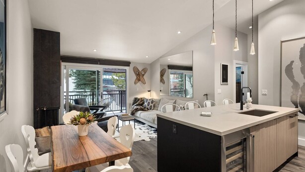 A modern kitchen with a central island, white chairs, and a dining table. - 700 Monarch Condos by iTrip Aspen Snowmass (Aspen)