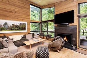 Een moderne woonkamer met een open haard, grote ramen en een gezellige zithoek.