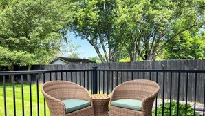 A deck with wicker chairs and a small table. - Welcome Race Fans! - Oversize Parking - Firepit - Mural - West Indy - Brownsburg (Indianapolis)