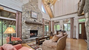 Un salón espacioso con chimenea de piedra, ventanas amplias y techo alto.