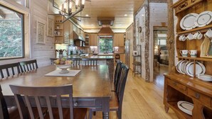 A spacious kitchen with wooden cabinets, a central island, and a dining area with a large wooden table and chairs.