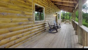 Une cabane en bois dotée d’un porche couvert, de fauteuils à bascule et d’un banc.