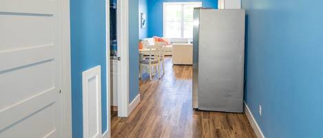 A hallway with wooden flooring, a white door, and a blue wall.