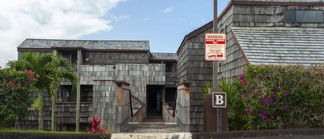 Un edificio con fachada de madera, un cartel que dice 'WARRENING' y un letrero de estacionamiento con la letra 'B'.