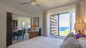 Une chambre d’hôtel avec un grand lit, un bureau et une vue sur l’océan.