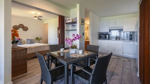 Un espace de vie compact comprenant un coin repas, une kitchenette et une chambre.