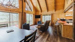 A wooden cabin interior with a dining table, chairs, a sofa, a TV, and a kitchen area. - Close to Wolf Creek, Fish San Juan River, Escape the Crowds (Pagosa Springs)