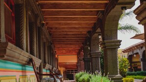 A covered corridor with tiled flooring, wooden beams, and benches along the side. - Gran Misiones Tequisquiapan (Tequisquiapan)