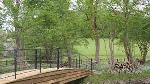 A wooden bridge over a stream with a metal railing, surrounded by trees and a grassy field. - 1 bedroom accommodation in Llanfyllin, near Welshpool (Llanfyllin, near Welshpool)