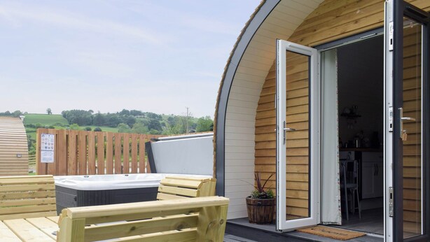 A wooden deck with a hot tub, wooden benches, and a door leading to a kitchen area. - 1 bedroom accommodation in Llanfyllin, near Welshpool (Llanfyllin, near Welshpool)