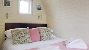 A neatly made bed with floral pillows, a pink blanket, and white towels. - 1 bedroom accommodation in Llanfyllin, near Welshpool (Llanfyllin, near Welshpool)