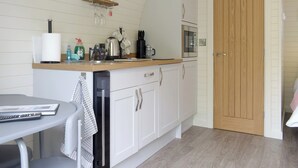 A compact kitchen with white cabinetry, a wooden countertop, and a microwave. There is a small shelf above the sink holding various kitchen items. - 1 bedroom accommodation in Llanfyllin, near Welshpool (Llanfyllin, near Welshpool)