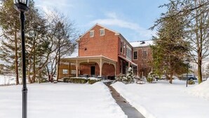 A brick building with a covered porch and a snow-covered pathway leading to it. - 2 bedroom, 1.5 baths, full kitchen, comfortable living space with free parking (Palmyra)