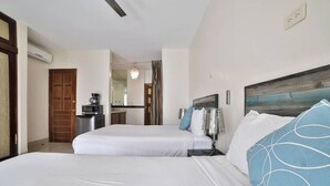 Ein Hotelzimmer mit zwei Betten, einer Kaffeemaschine, einem Spiegel und Blick ins Freie.