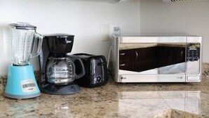 Eine Küchenarbeitsplatte mit Mixer, Kaffeemaschine und Mikrowelle.