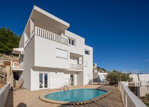 Relax by the outdoor pool surrounded by a garden with a scenic view.