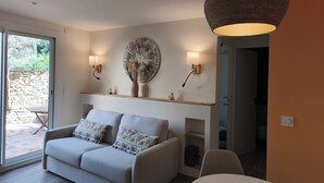 A modern living room with a sofa, a dining table, a large wall art piece, and two wall-mounted lamps.