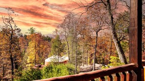 A wooden deck overlooking a forested area with a cabin. - Luxury Yurt Cozy & Fun 1br/1bth, experience it, Private Deck w Grill & HotTub (Pigeon Forge)