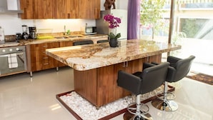 Una cocina moderna con armarios de madera, una isla de mármol y taburetes de bar.