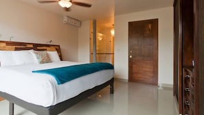 Un dormitorio con cama, ventilador de techo, armario de madera y una puerta.
