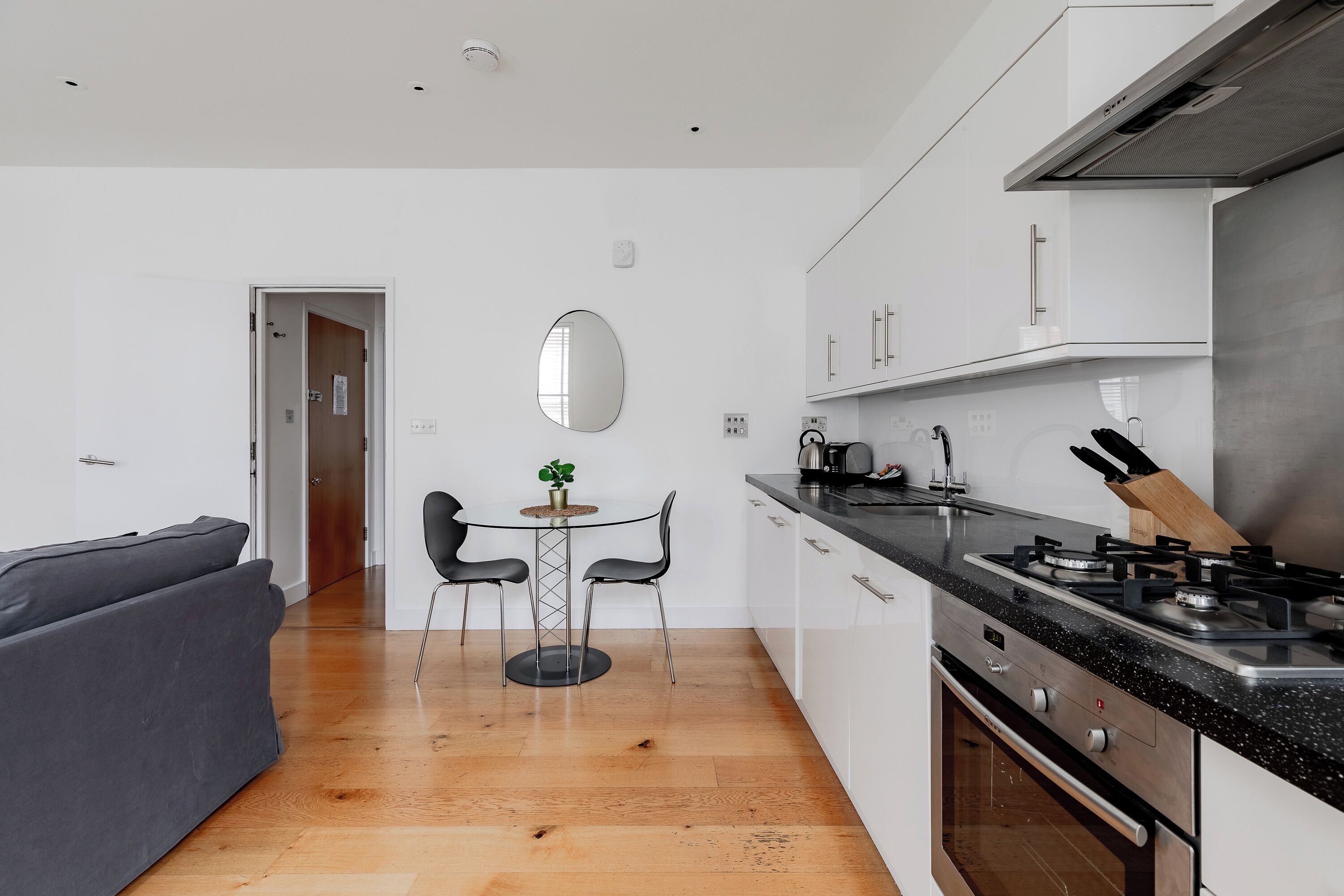 A modern kitchen with white cabinets, a black countertop, and a stainless steel range hood.