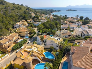 A coastal residential area with houses, a swimming pool, and a view of the sea.