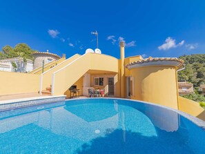 Une piscine avec un espace patio, un barbecue et une vue sur le paysage environnant.