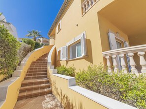 Un immeuble à plusieurs étages, doté d’un escalier menant aux étages supérieurs et entouré de verdure.