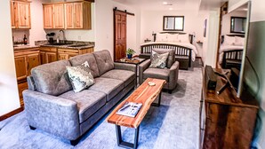 Ein modernes Wohnzimmer mit einem grauen Sofa, einem Holztisch und einem Fernsehschrank.