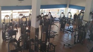 A gym with various exercise machines and a wooden floor.
