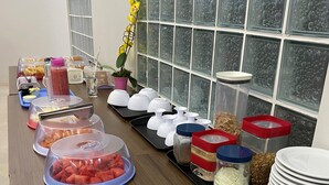A buffet table with various food items and condiments, including fruits, dairy products, and containers.