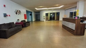 A spacious lobby with a reception desk, a sofa, and a potted plant.