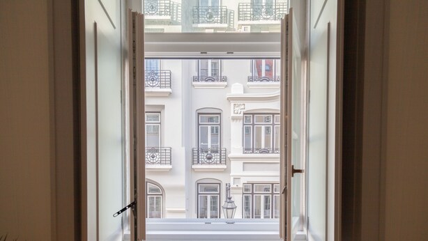 A view through a window of a building with multiple balconies and a street view.