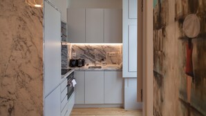 Een moderne keuken met marmeren aanrechtbladen, witte kasten en een houten vloer.