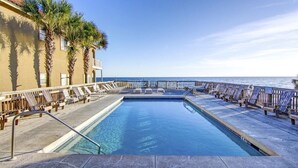 Un área de piscina con sillones de descanso y vista al océano.
