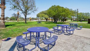 A park with picnic tables and benches, surrounded by trees and a clear sky. - OYO Hotel Luling TX Downtown I-10/US-90 (Luling)