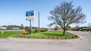 A Luling Inn sign, a parking lot, and a landscaped area with trees and shrubs. - OYO Hotel Luling TX Downtown I-10/US-90 (Luling)