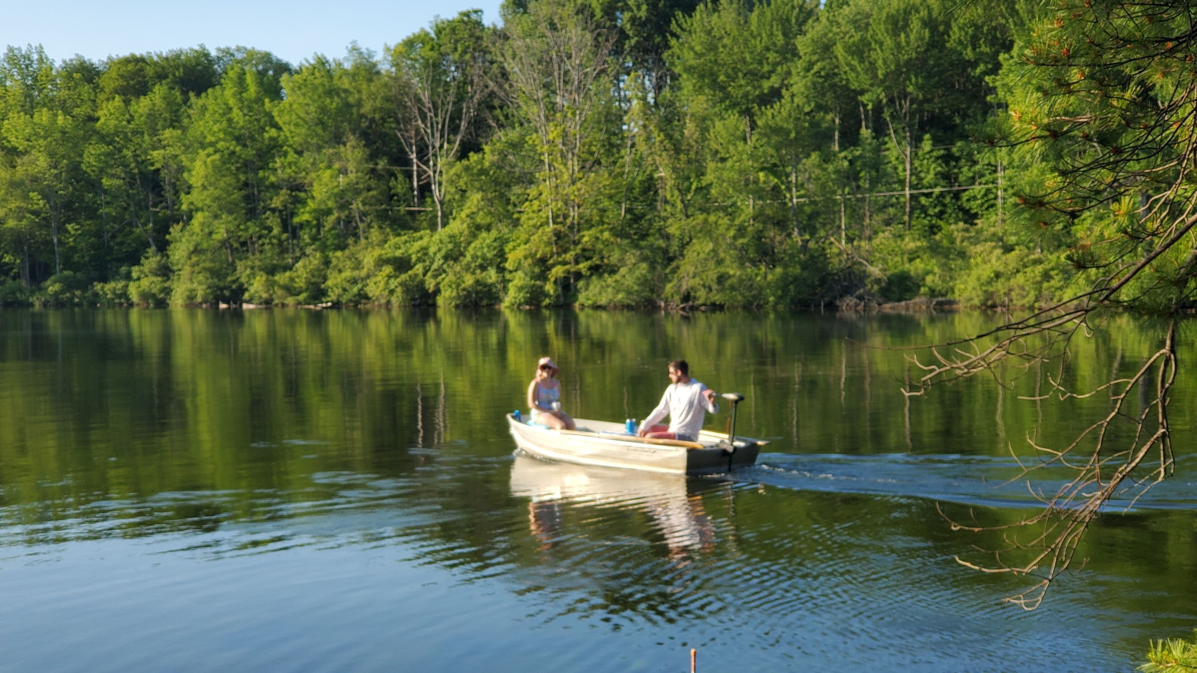 A calm lake with a boat carrying two people.