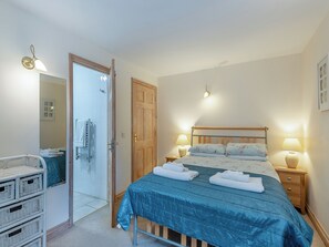 Une chambre à coucher avec un lit, des lampes de chevet, une porte en bois, un miroir et un luminaire fixé au mur.