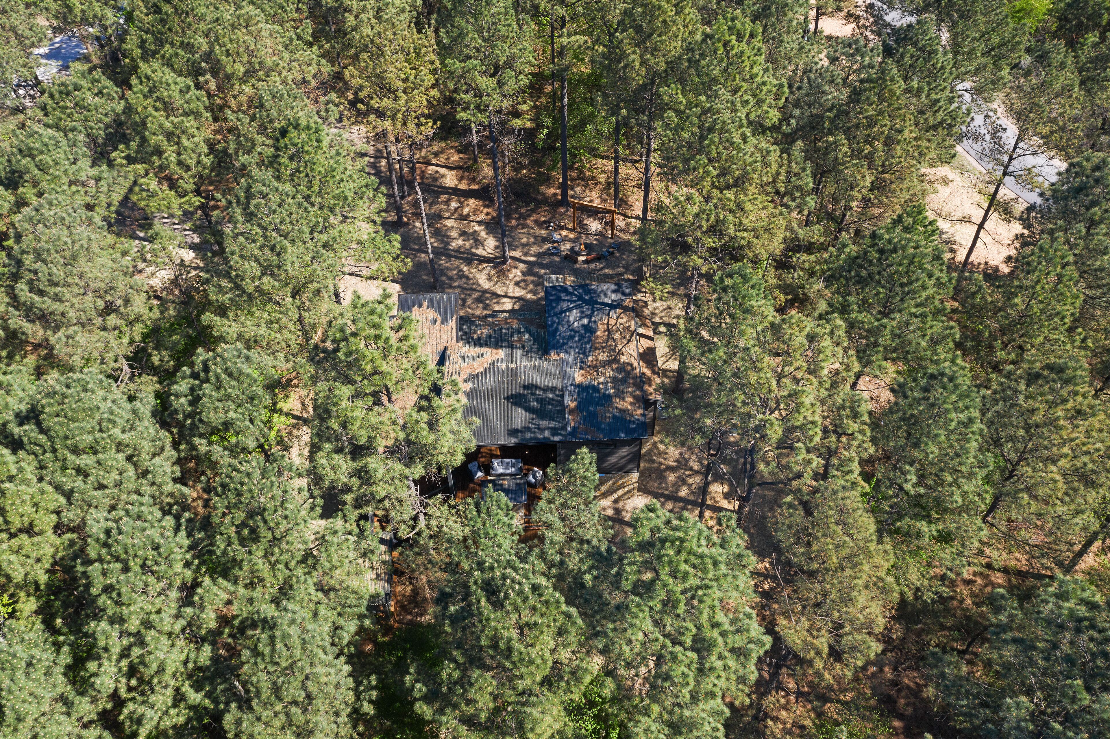 Vista aérea de una cabaña rodeada de densos pinos.