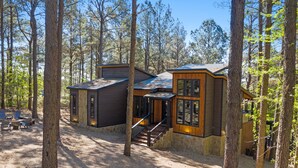 A cabin with a staircase leading to a deck, surrounded by tall trees. - Modern and Luxury Cabin, 2 BR 2.5 Bath, Sleeps 9 max, 2 Pets Max with Pet Fee (Broken Bow)