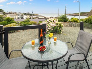 Een glazen tafel met een fles, een glas sinaasappelsap en een bord aardbeien.