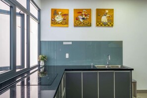 Une cuisine moderne avec un plan de travail noir, un évier en acier inoxydable et une fenêtre offrant une belle vue.