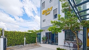A hotel with a modern facade, a visible entrance, and a seating area outside. - Richy Hotel (Da Lat)