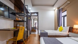 A hotel room with two beds, a desk, a chair, and a wardrobe. - Richy Hotel (Da Lat)