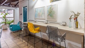 A modern bar area with a wooden ceiling, two wall-mounted maps, and a counter with bar stools. - Botánica Casa Hotel (Medellín)