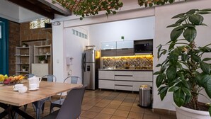 A modern kitchen with a dining area, featuring a wooden table, chairs, and a potted plant. - Botánica Casa Hotel (Medellín)