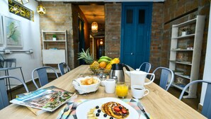 A breakfast table with a plate of pancakes, a magazine, and a fruit bowl. - Botánica Casa Hotel (Medellín)